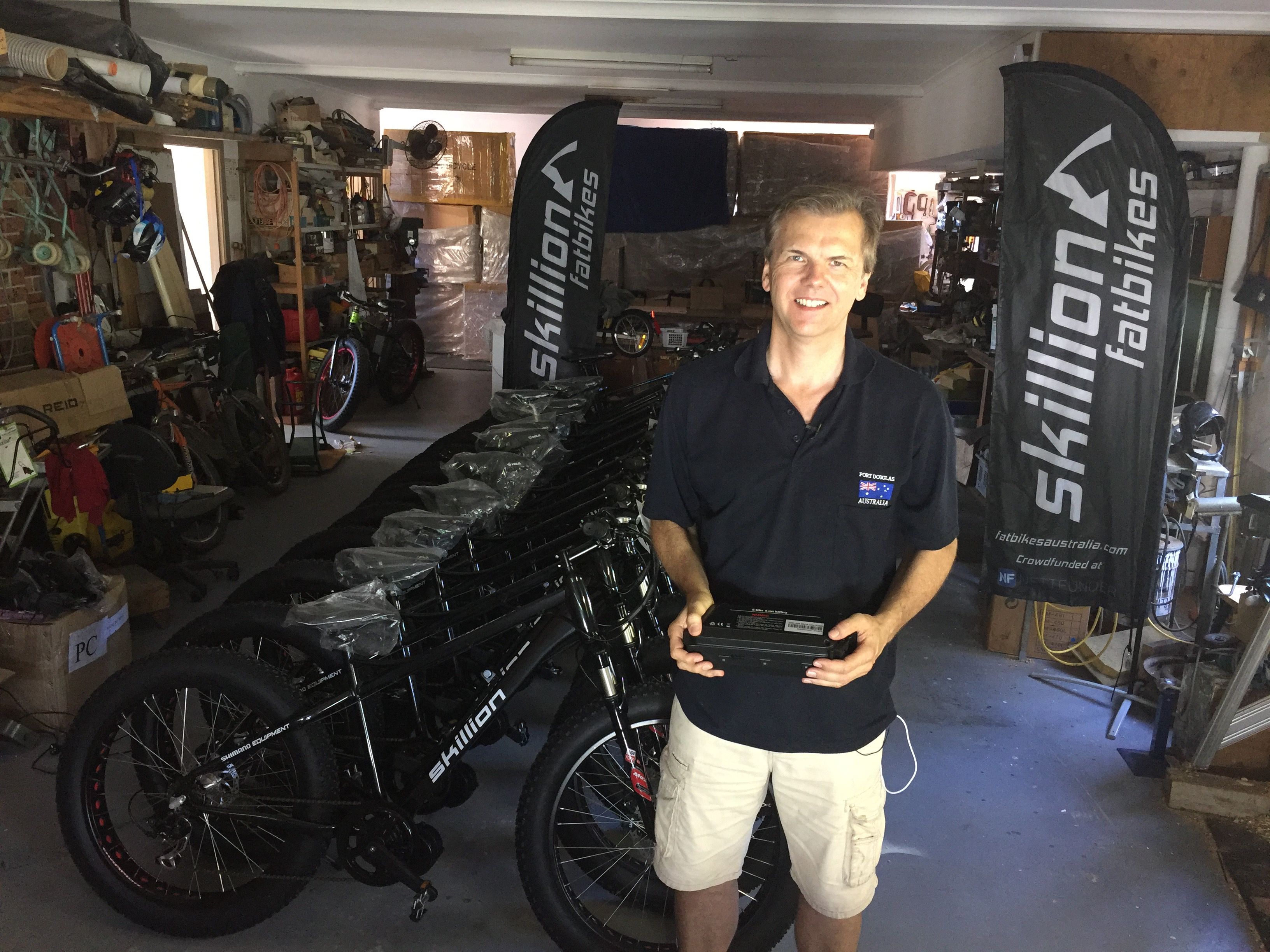Man holding battery in front of Skillion 2 ebikes